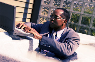 Businessman on laptop in a hot tub