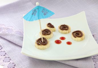 Sliced banana with chocolate topping and cocktail umbrella
