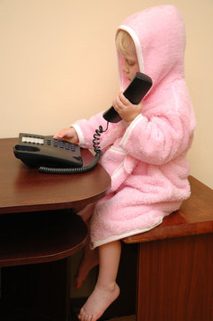 The child in a dressing gown calls by phone