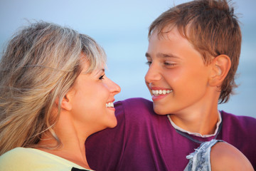 smiling boy and young woman on beach in evening, Looking against