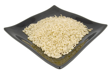 black plate of brown rice isolated on white background