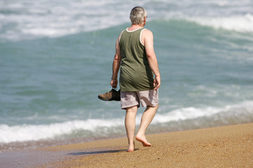 viel homme en train de marcher sur la plage