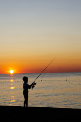 Young boy is fishing on the beach