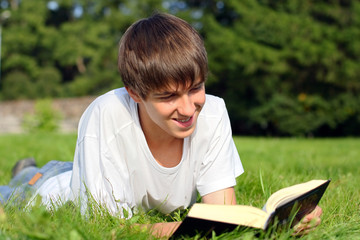 The teenager reads the book on a summer meadow