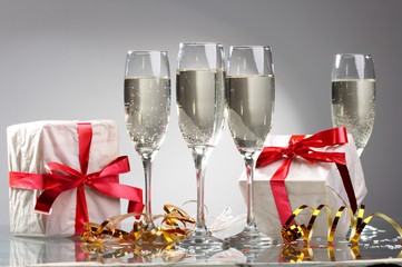 Glasses of champagne, gifts with red tapes and bows