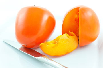 two ripe persimmons and steel knife