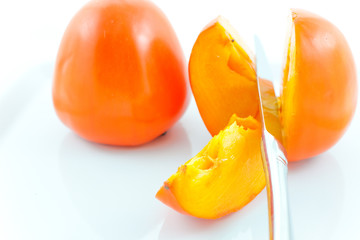 two ripe persimmons and steel knife
