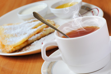 Tea and pancakes  with powdered sugar