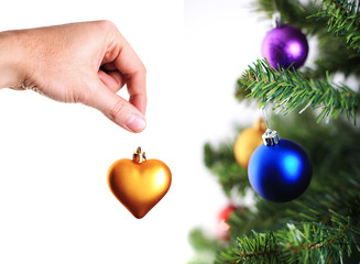 hand decorating christmas tree with gold heart