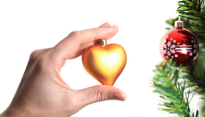 hand decorating christmas tree with golden heart