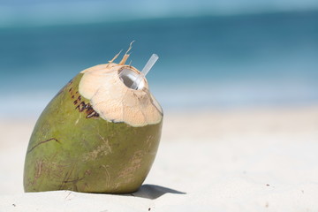 Kokos drink leżący na piasku na plaży na tle morza