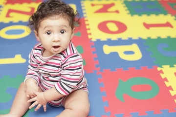 Baby sitting on an alphabet play mat