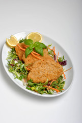 breaded fish steak with organic herbs on a plate