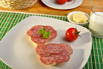 half bread roll with salami on a plate