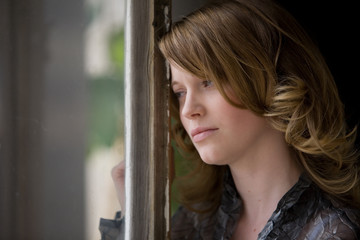 Frau schaut traurig aus dem Fenster