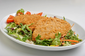breaded fish steak with organic herbs on a plate