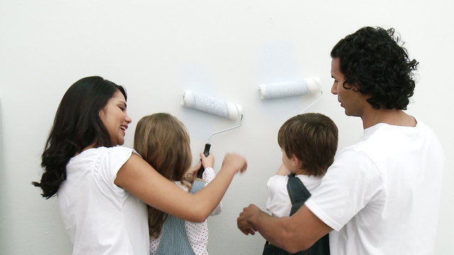Family painting with brushes a wall at home