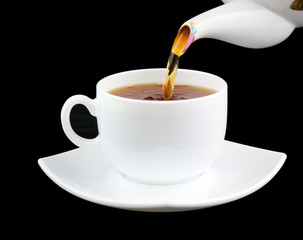 Pouring tea to white cup isolated on black