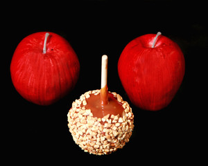 Caramel apple and two red apples on a black background