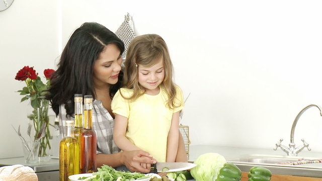 Mother and little girl cutting vegetables