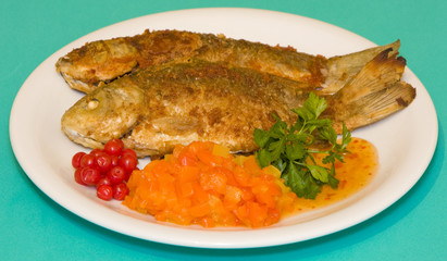 Fried fish in plate on a green background