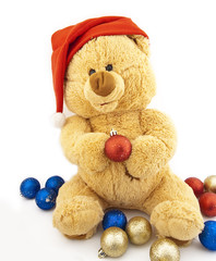 Toy bear in a Christmas cap and with Christmas-tree decorations