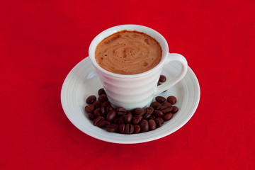 cup with coffee and grain expressed on red background