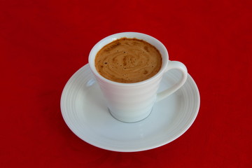 cup with coffee and grain expressed on red background