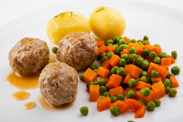 Roasted meatballs with boiled potatoes, peas and carrot