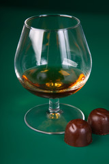 Glass with cognac (whisky) on a green background