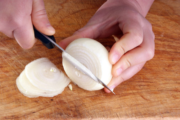 cut organic onion, knife and two hands