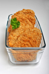 breaded fish steak with organic herbs in a glass bowl