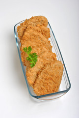 breaded fish steak with organic herbs in a glass bowl