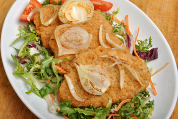 breaded fish steak with organic herbs on a plate