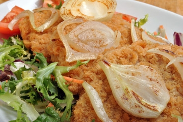 breaded fish steak with organic herbs on a plate