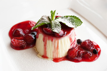 panna cotta  on white plate with berry sauce