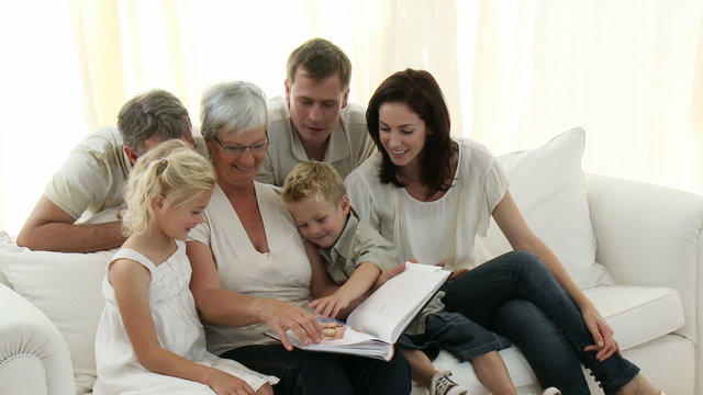 Happy Family sitting on sofa looking at a Photo Album at home