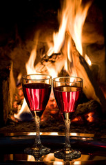glasses with red wine at a fire in the fireplace