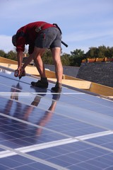 ouvrier vissant des panneaux solaires