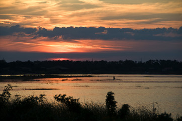 Beautiful red sunset over a lake with two fishermen in a boat