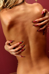 Woman fingers with decorated nails on the body.