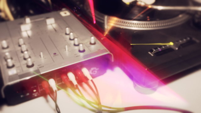 a pan across dj turntables with abstract light patterns