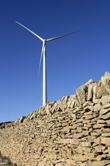 Fototapeta premium Electric windmills with a masonry rural wall
