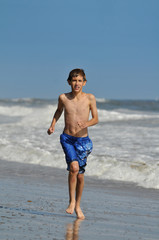 Fototapeta na wymiar Young boy running at the beach