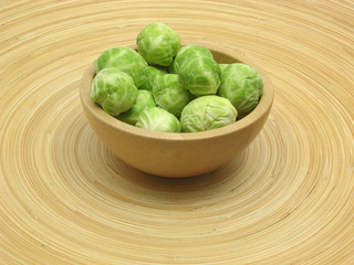 Holzschale mit Rosenkohl auf Bambusteller