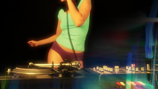 beautiful young female dj, behind the decks at a club