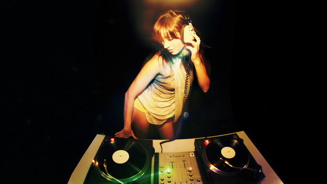 beautiful young female dj, behind the decks at a club