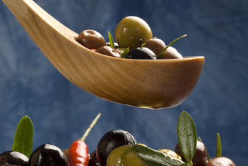 Assorted olives in a wood spoon.