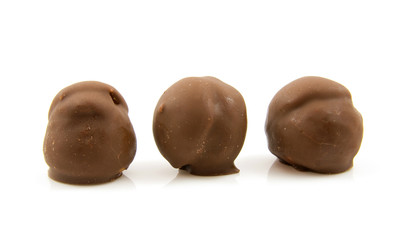Three brown chocolate cream puffs in a row over white background