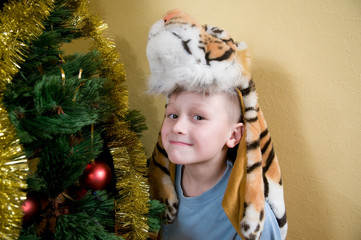 Boy in a mask of a tiger at achristmas tree.